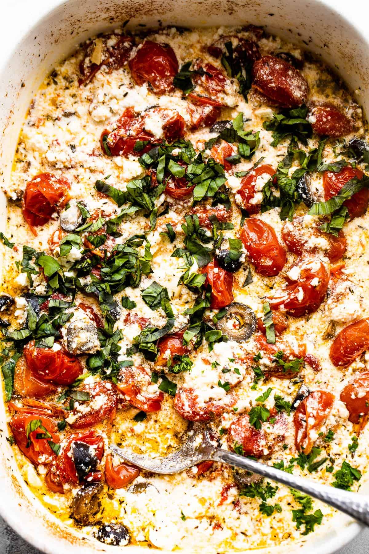 baked feta cheese with baked tomatoes, olives, and herbs