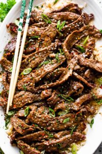 chopsticks placed over thinly sliced korean beef bulgogi