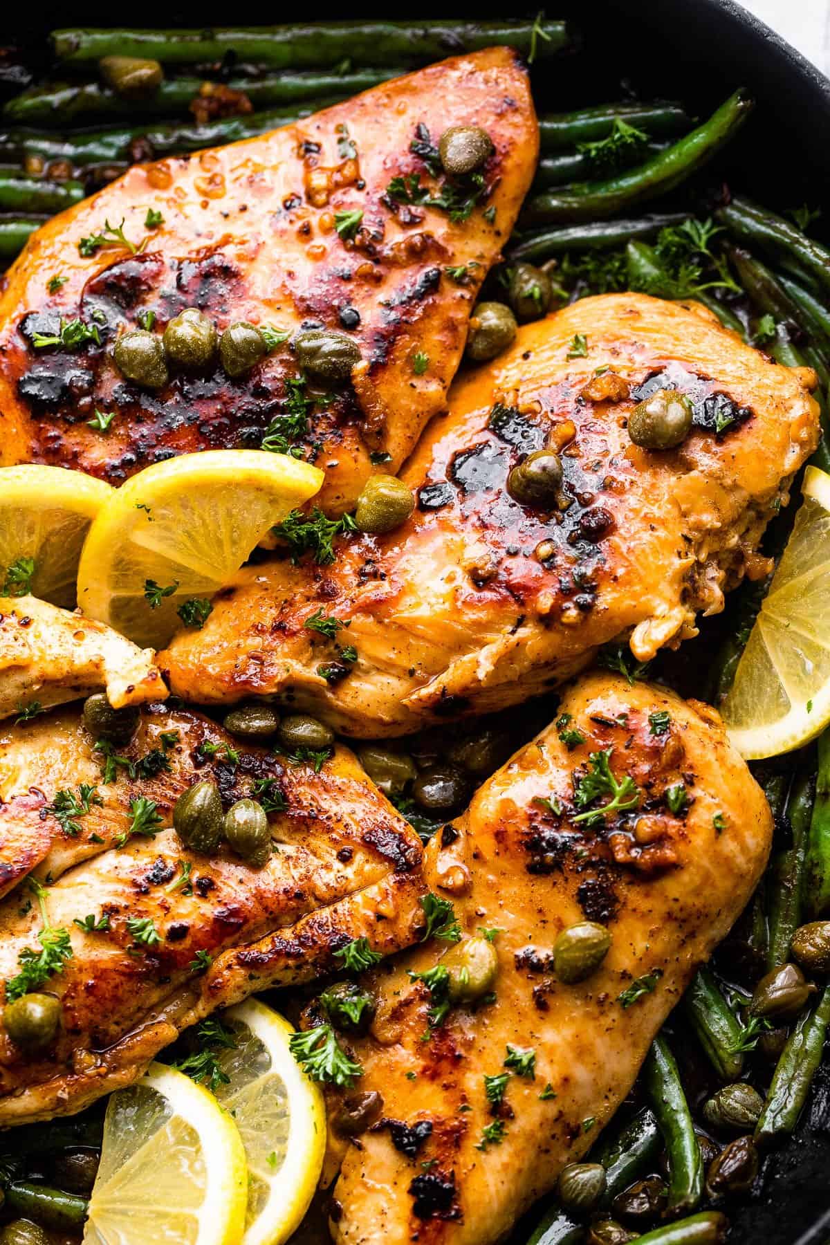 overhead shot of chicken breasts topped with capers and lemon slices