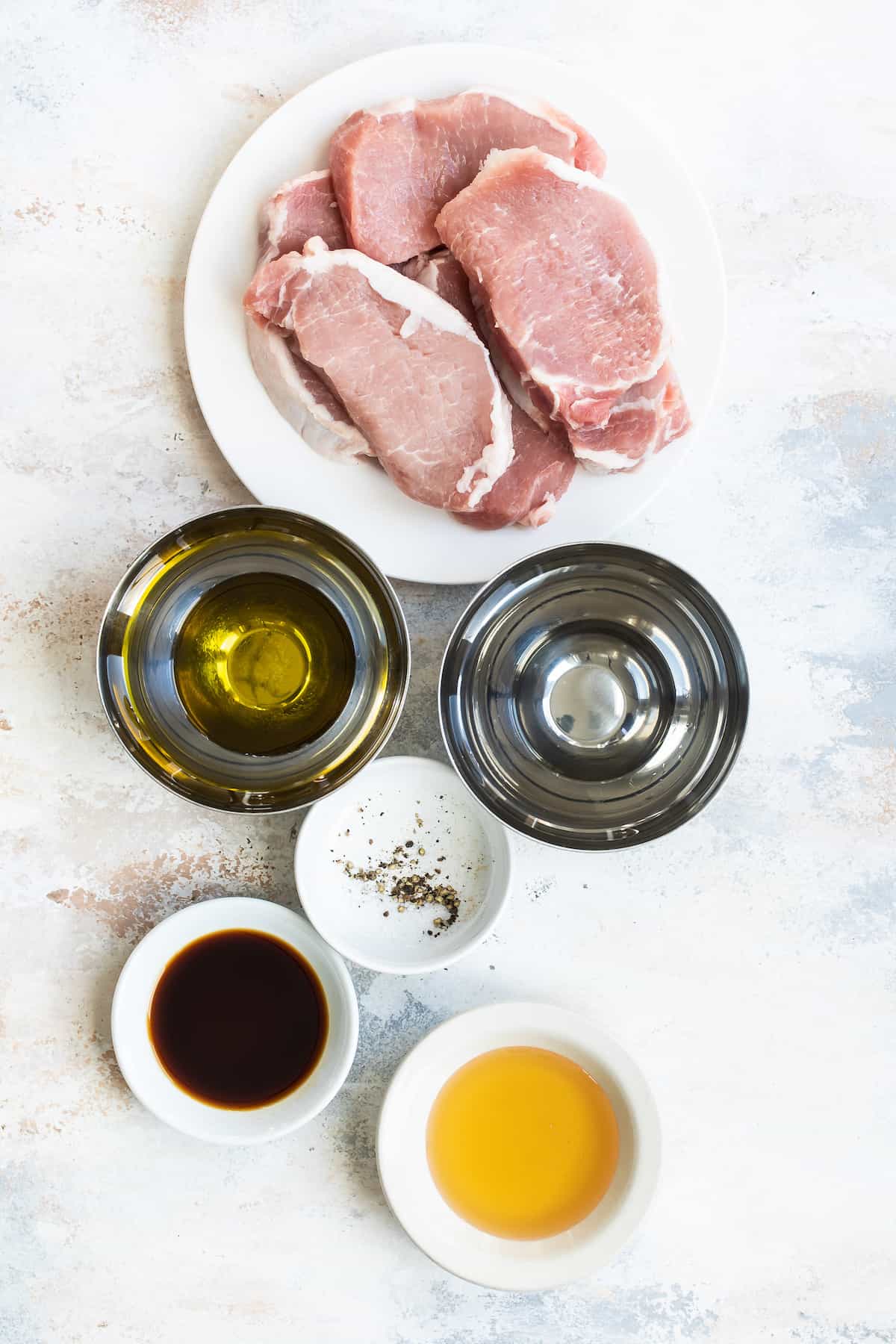 Pork Chops, Salt, Pepper and the Rest of the Ingredients on a Countertop