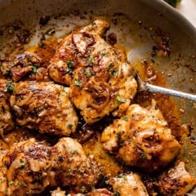 five cooked chicken thighs in a skillet