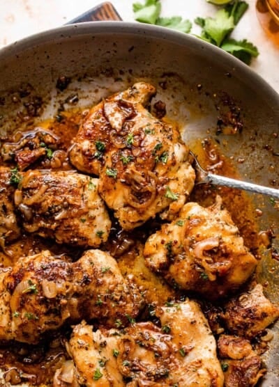 five cooked chicken thighs in a skillet