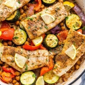 four mahi mahi fillets arranged over zucchini, chickpeas, onions, and peppers