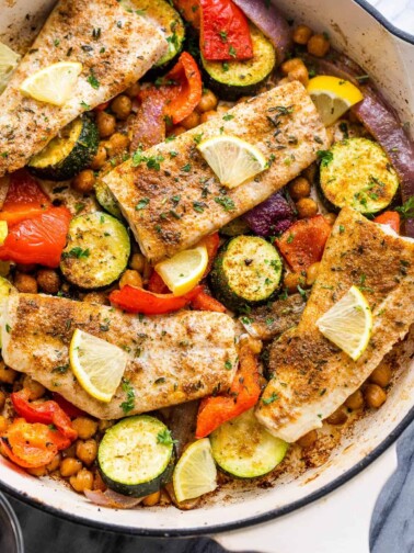 four mahi mahi fillets arranged over zucchini, chickpeas, onions, and peppers