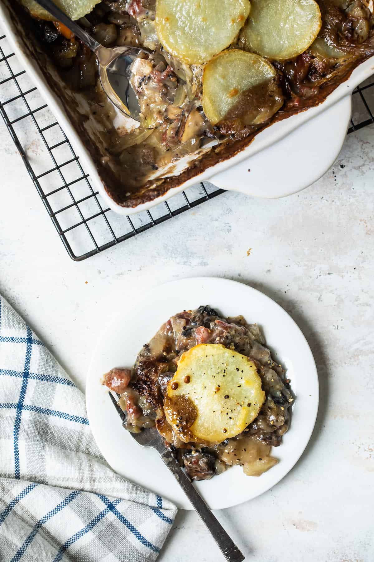 A Plate Full of Veggie Moussaka Next to a Pan with One Serving Gone