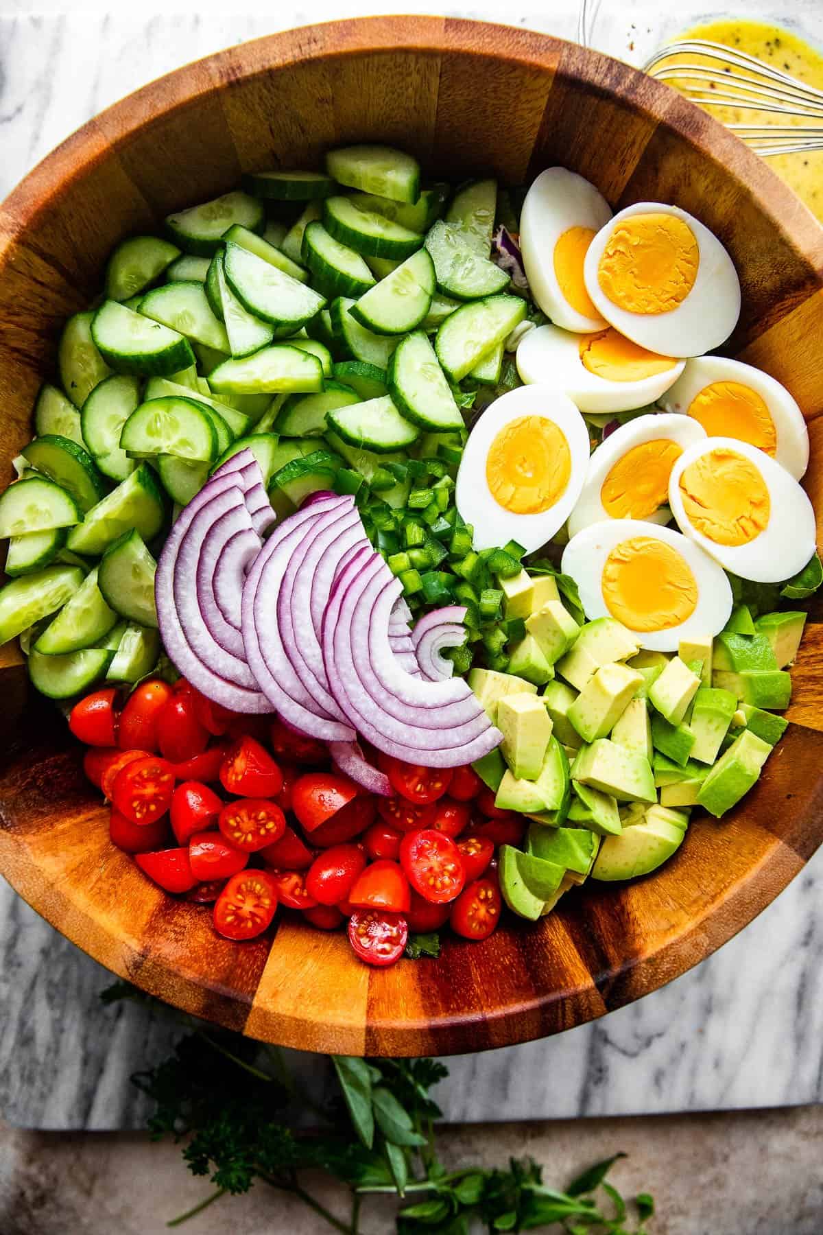 Eggs, Cucumbers, Avocado, and Tomatoes in a wooden salad bowl