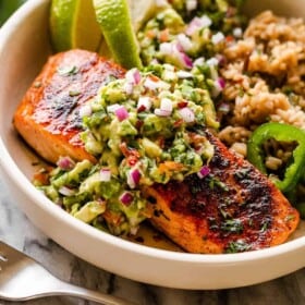 salmon fillet in a bowl atop of rice and served with avocado salsa