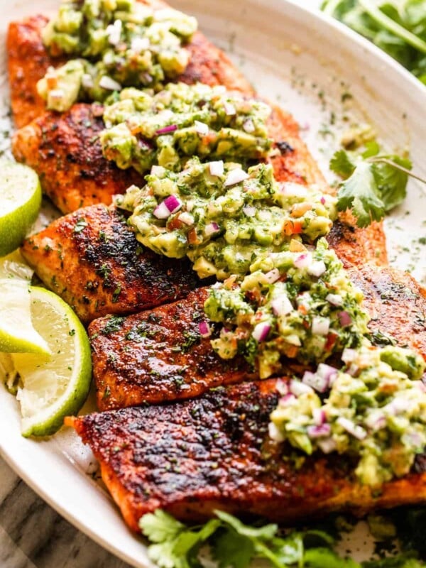 side shot of grilled salmon fillets topped with avocado salsa
