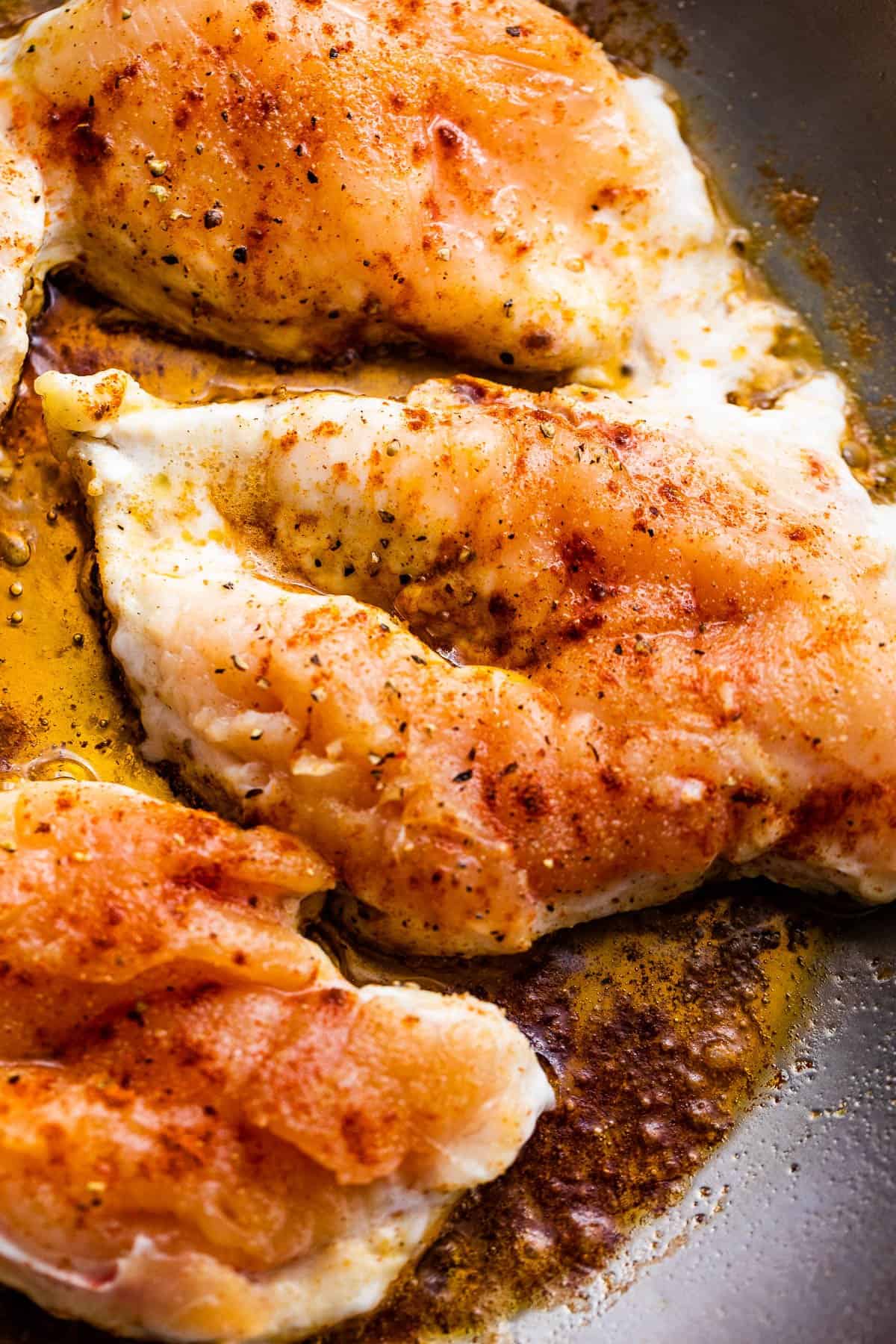 cooking raw chicken breasts in a skillet