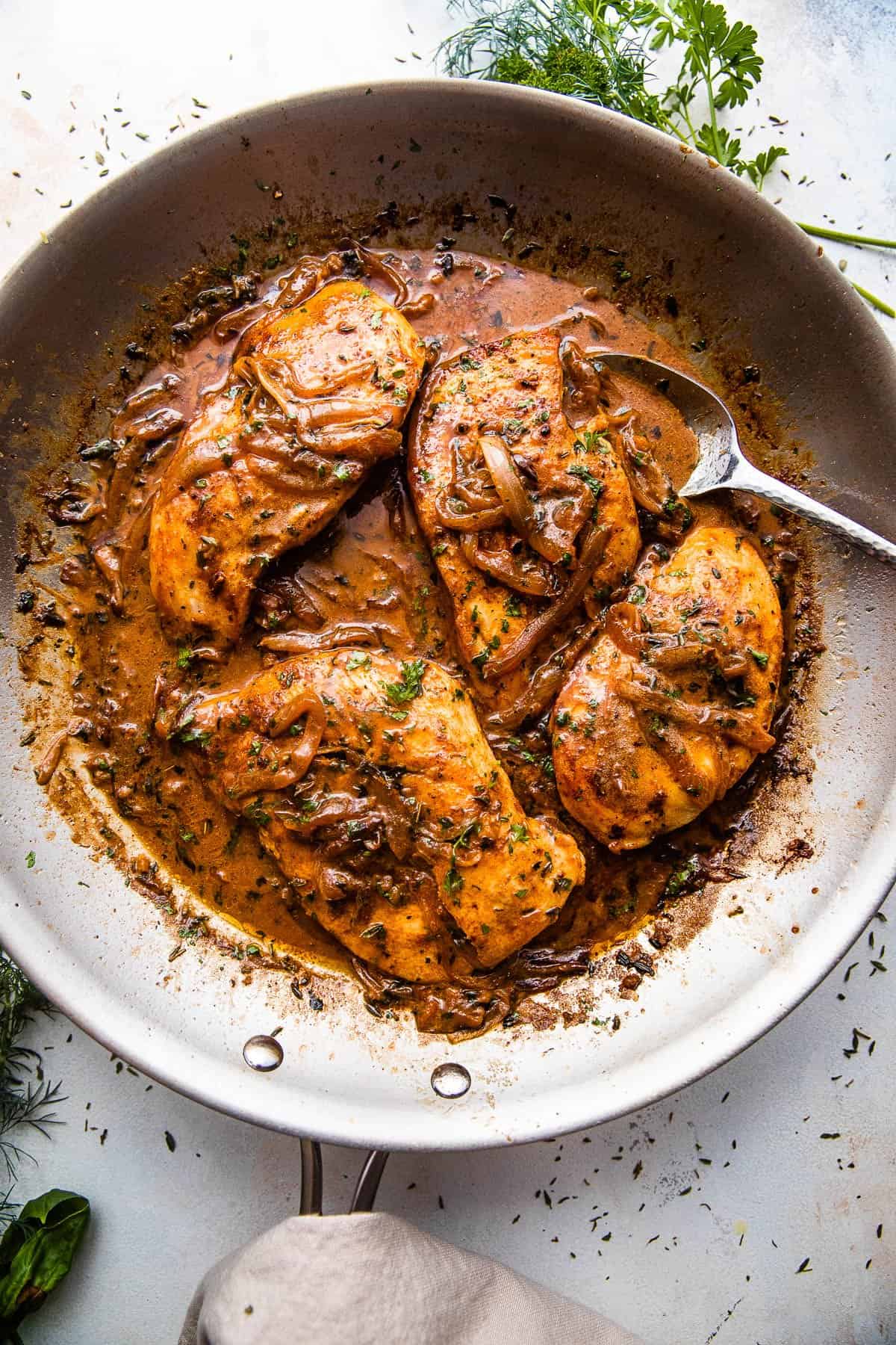 wide overhead shot of chicken breasts in a skillet with gravy