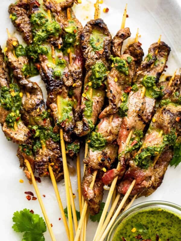 eight Grilled Steak Skewers served on a plate and topped with chimichurri sauce