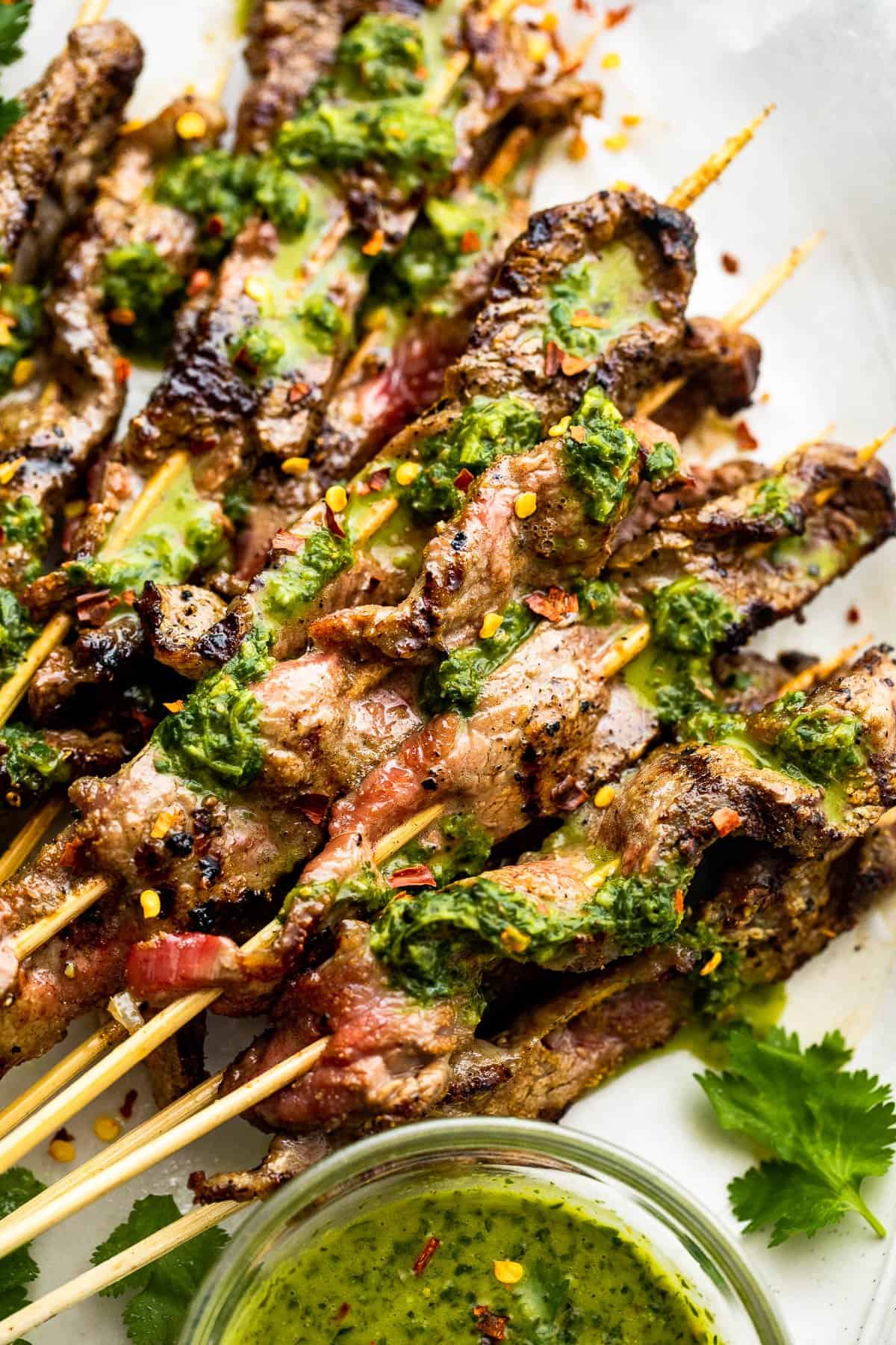 up close shot of Grilled Steak Skewers served topped with chimichurri sauce