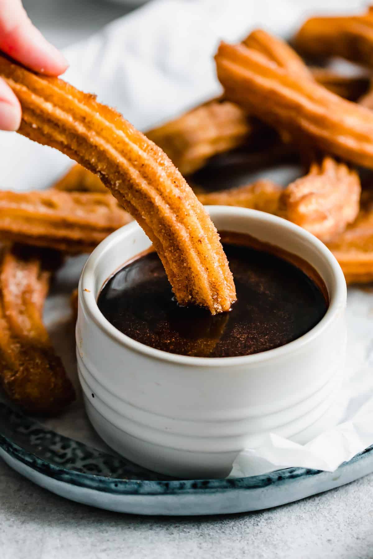 dipping churros into a bowl of chocolate sauce