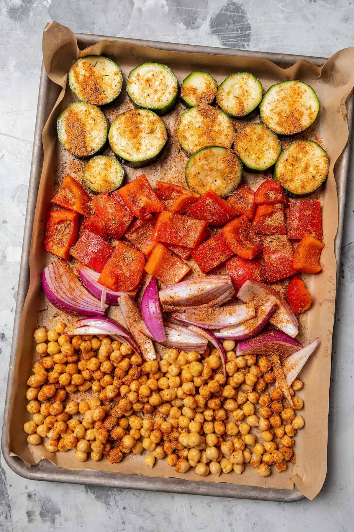 Chickpeas and chopped vegetables arranged on a lined sheet pan.