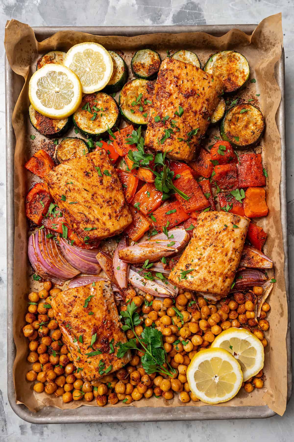 Overhead view of baked mahi mahi with crispy chickpeas and roasted vegetables on a sheet pan.