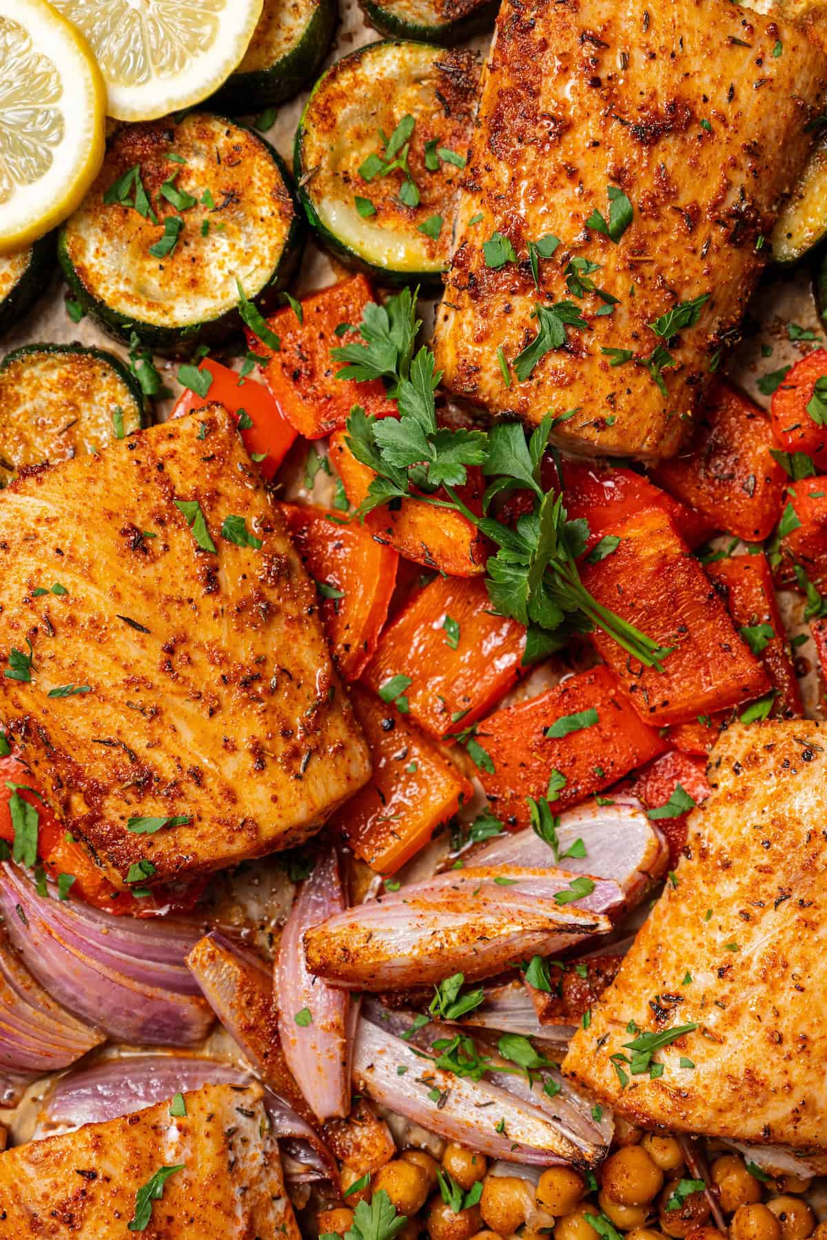 Overhead view of baked mahi mahi with crispy chickpeas and roasted vegetables on a sheet pan.