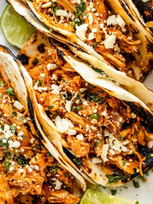 three chicken tinga tacos arranged on a plate and topped with cheese