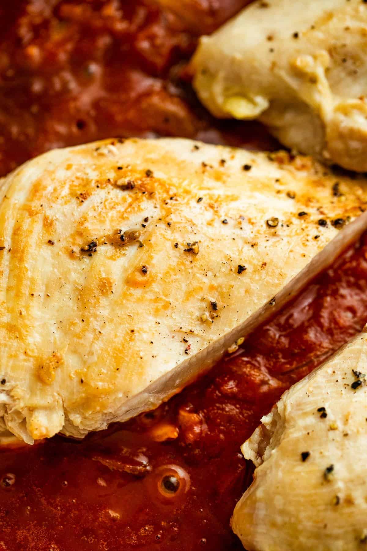 chicken breasts nestled in a tomato puree sauce