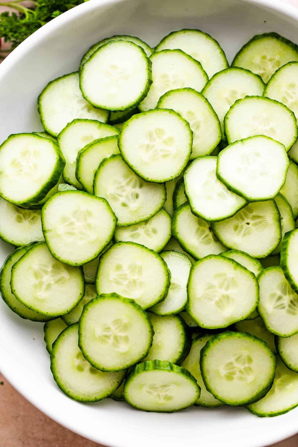slices of cucumbers in a white salad bowl