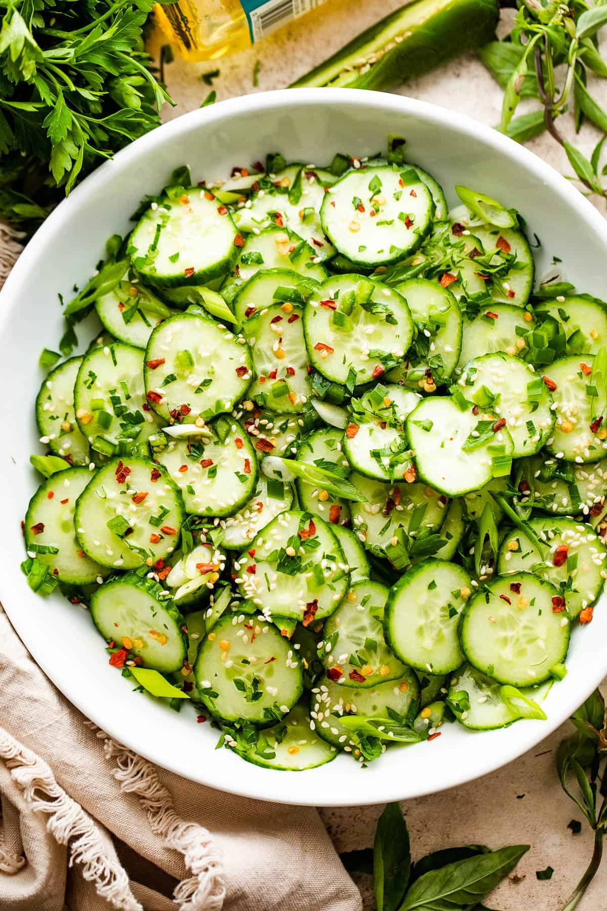 slices of cucumbers topped with sesame seeds, red pepper flakes, and green onions