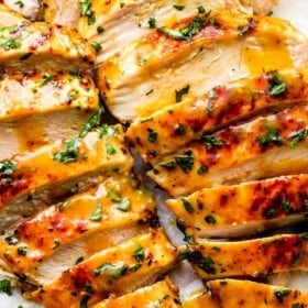 two grilled honey mustard chicken breasts cut into thin slices and served with honey mustard sauce on the side