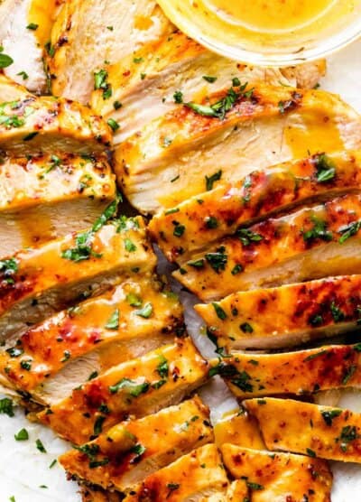 two grilled honey mustard chicken breasts cut into thin slices and served with honey mustard sauce on the side