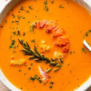 soup bowl with lobster bisque garnished with lobster meat and rosemary