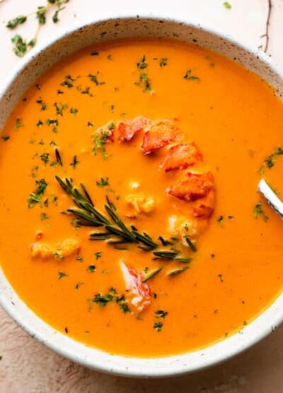 soup bowl with lobster bisque garnished with lobster meat and rosemary