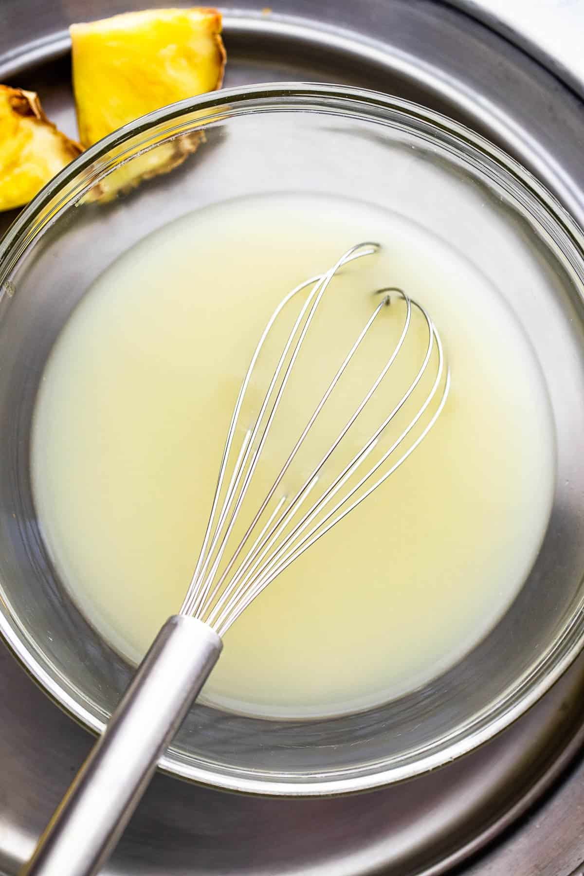 whisking together pineapple juice with coconut milk