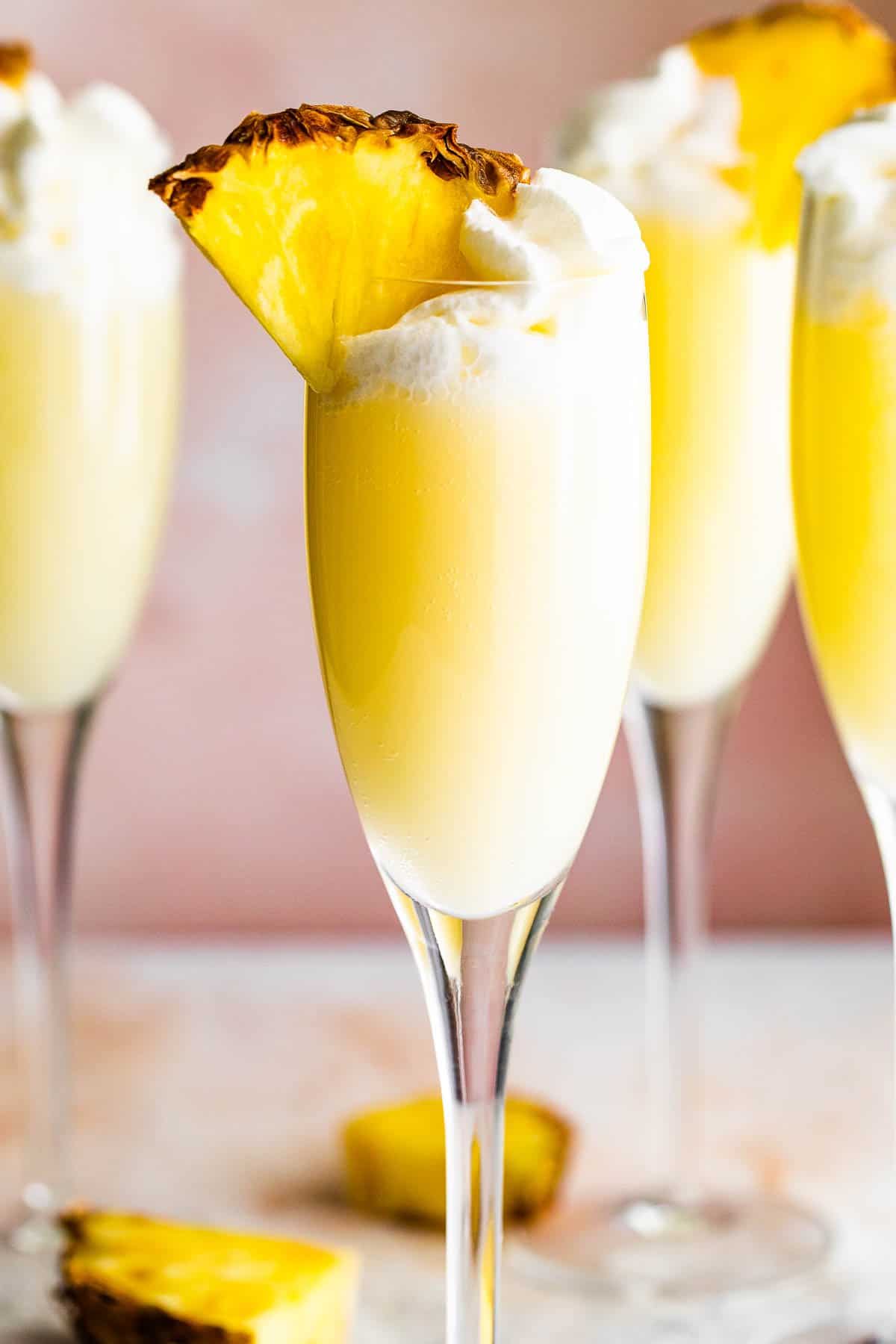 up close photo of champagne flutes with pineapple mimosas