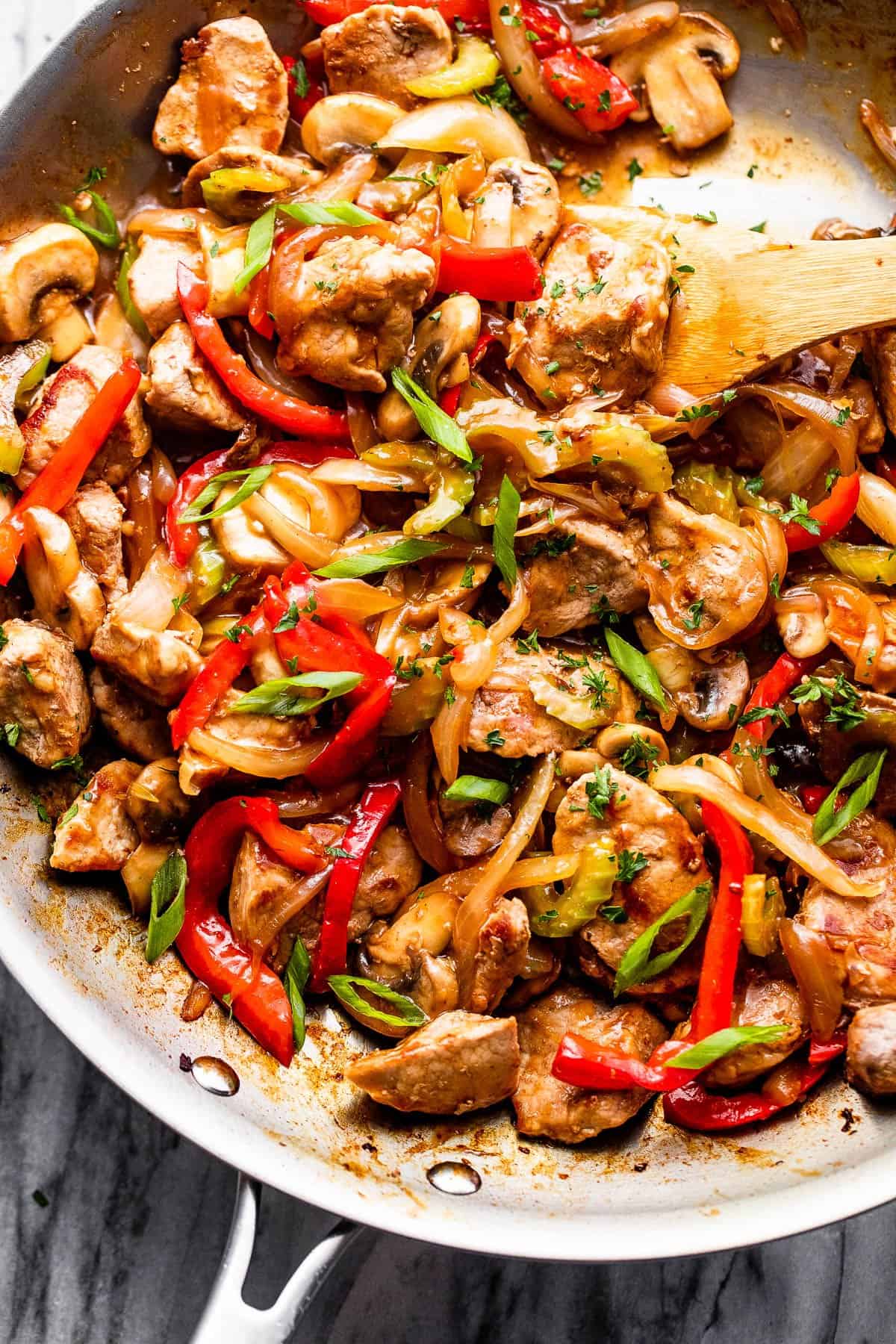 Cooking pork chop stir fry in a stainless skillet.