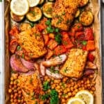 Overhead view of baked mahi mahi with crispy chickpeas and roasted vegetables on a sheet pan.