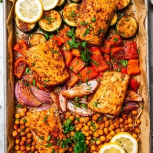 Overhead view of baked mahi mahi with crispy chickpeas and roasted vegetables on a sheet pan.