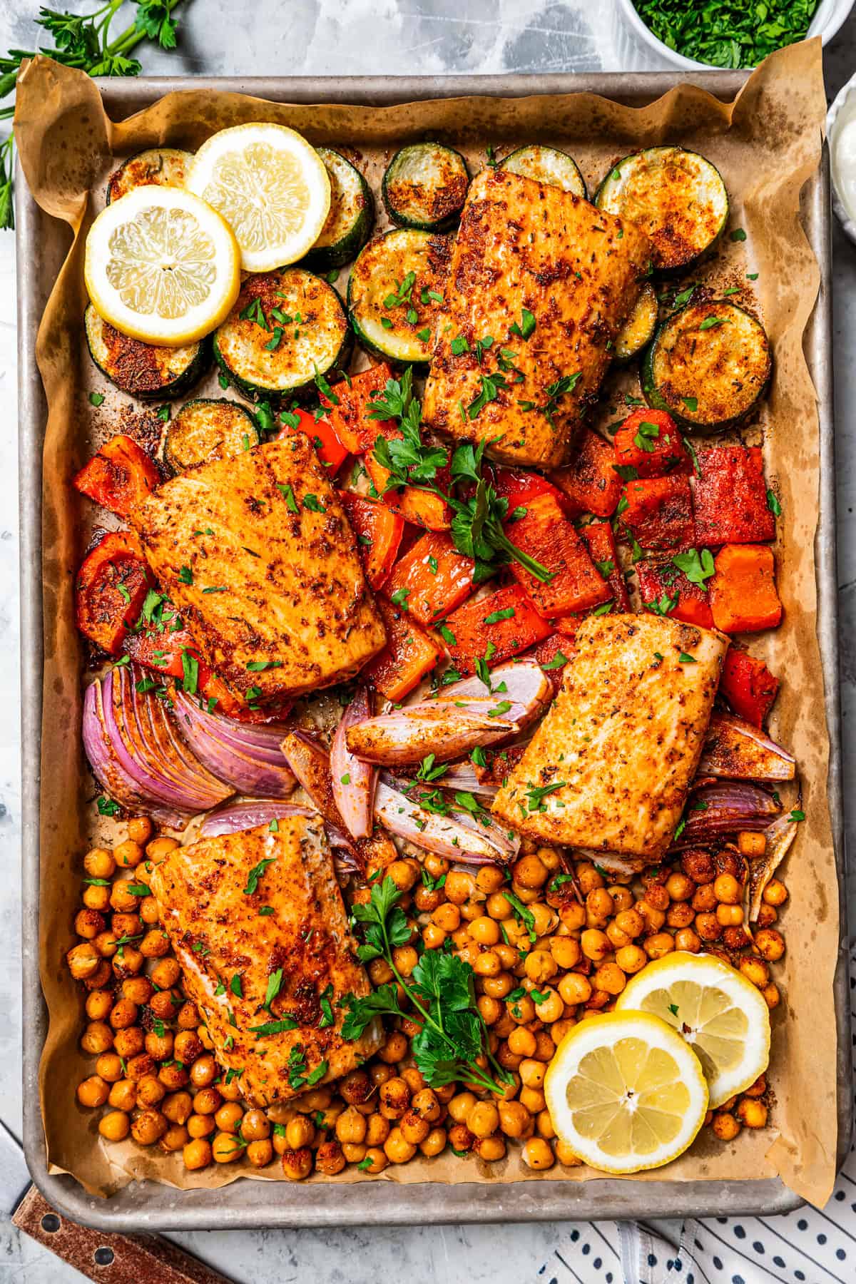 Overhead view of baked mahi mahi with crispy chickpeas and roasted vegetables on a sheet pan.