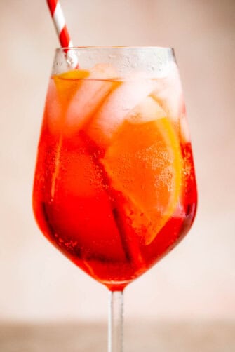Campari Spritz in a tall stemmed glass served with a red and white straw