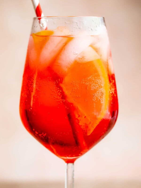 Campari Spritz in a tall stemmed glass served with a red and white straw