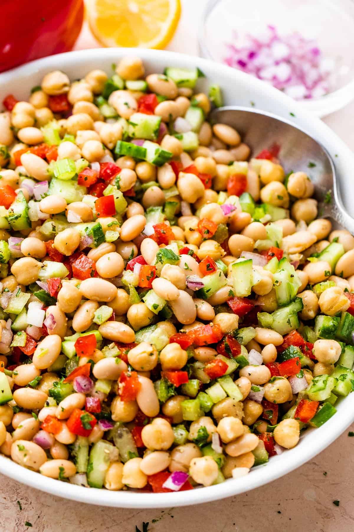 side shot of a salad bowl with chickpea salad and a spoon inside the bowl