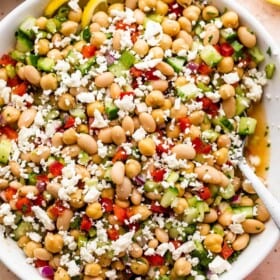 overhead shot of a white salad bowl with chickpea salad topped with crumbled feta cheese