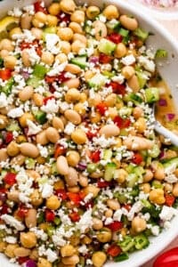 overhead close up shot of a white salad bowl with chickpea salad topped with crumbled feta cheese