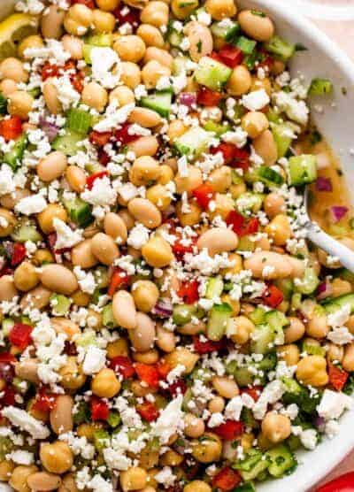 overhead close up shot of a white salad bowl with chickpea salad topped with crumbled feta cheese