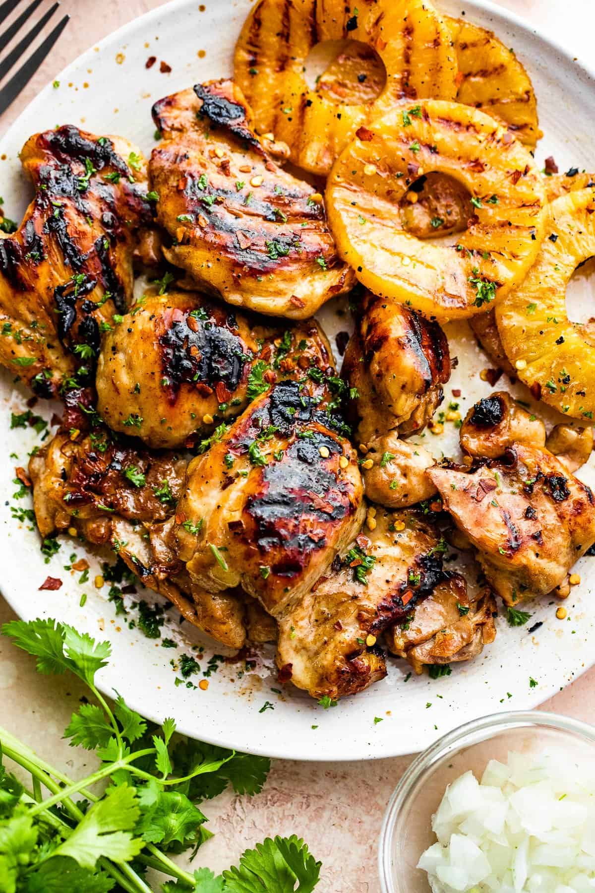 grilled chicken thighs and pineapples served on a white round plate