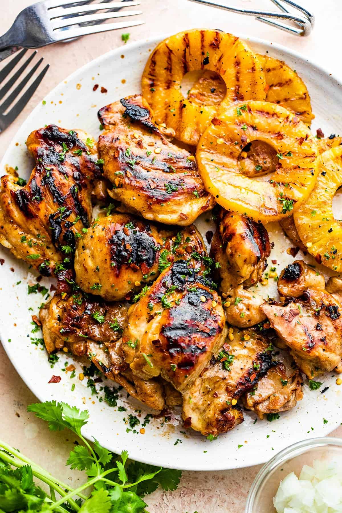 grilled chicken thighs and pineapples served on a white round plate