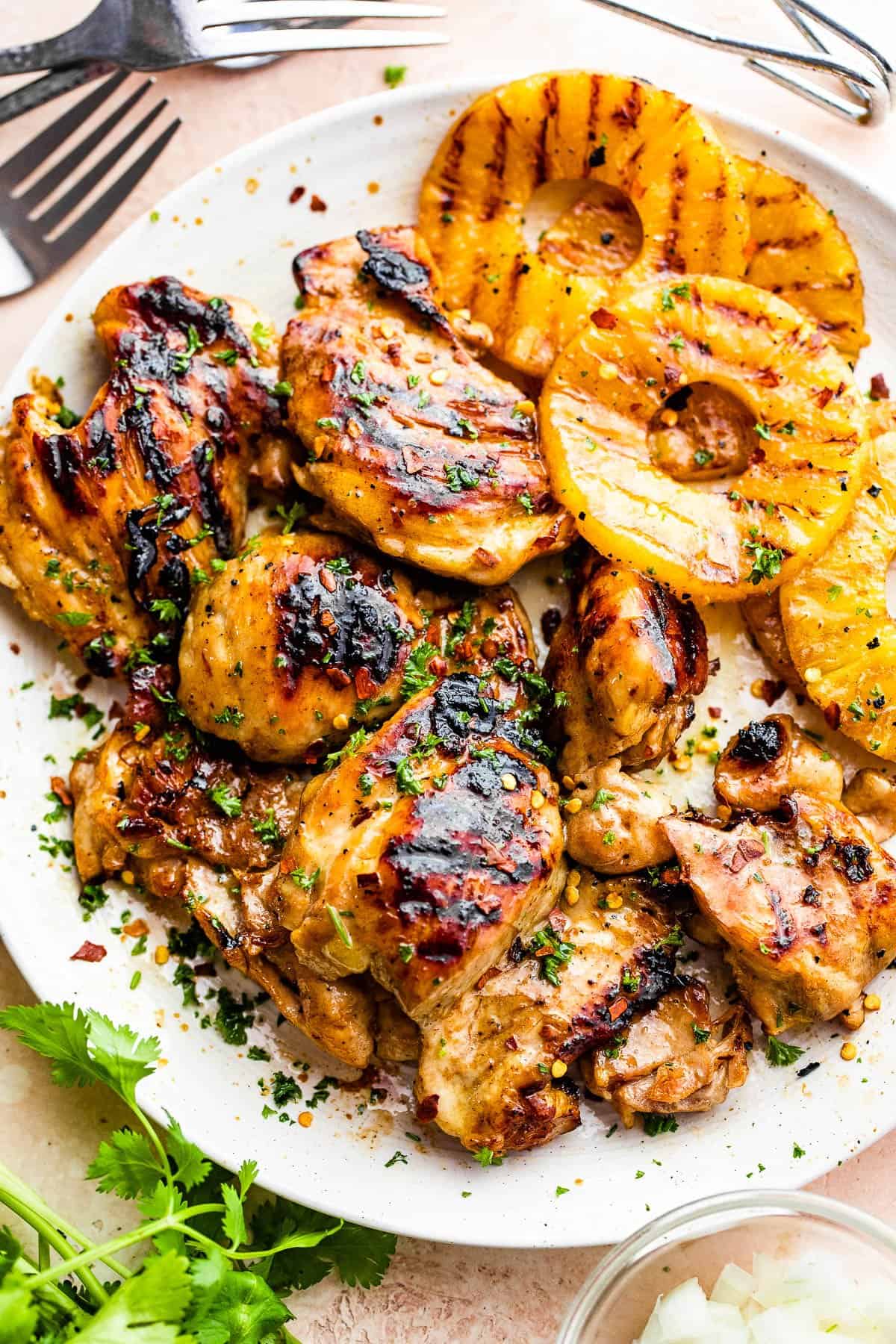 grilled chicken thighs and pineapples served on a white round plate