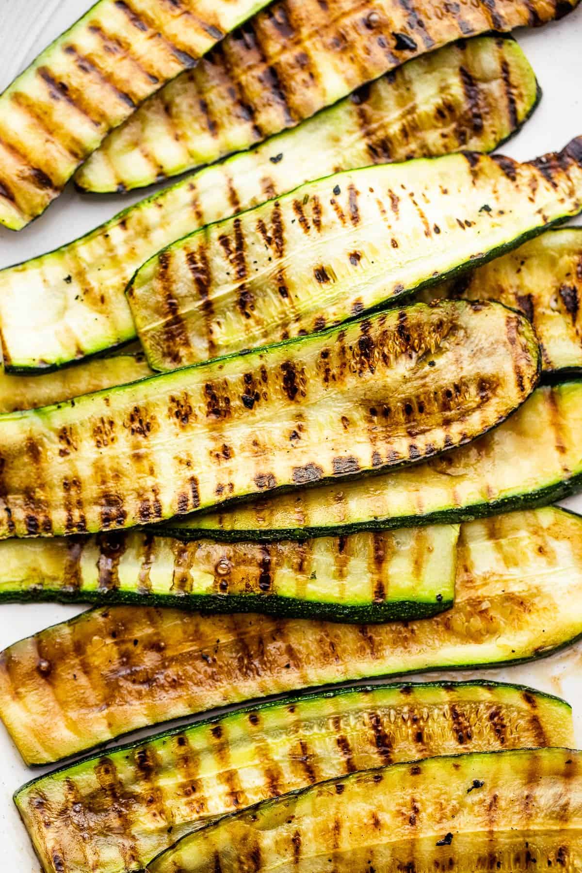 Grilled zucchini slices set on a white backdrop.
