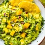 Overhead view of homemade guacamole with mango in a bowl with tortilla chips.