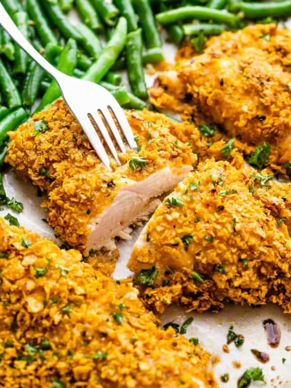 cutting into oven fried chicken breasts and holding one part of the chicken with a fork