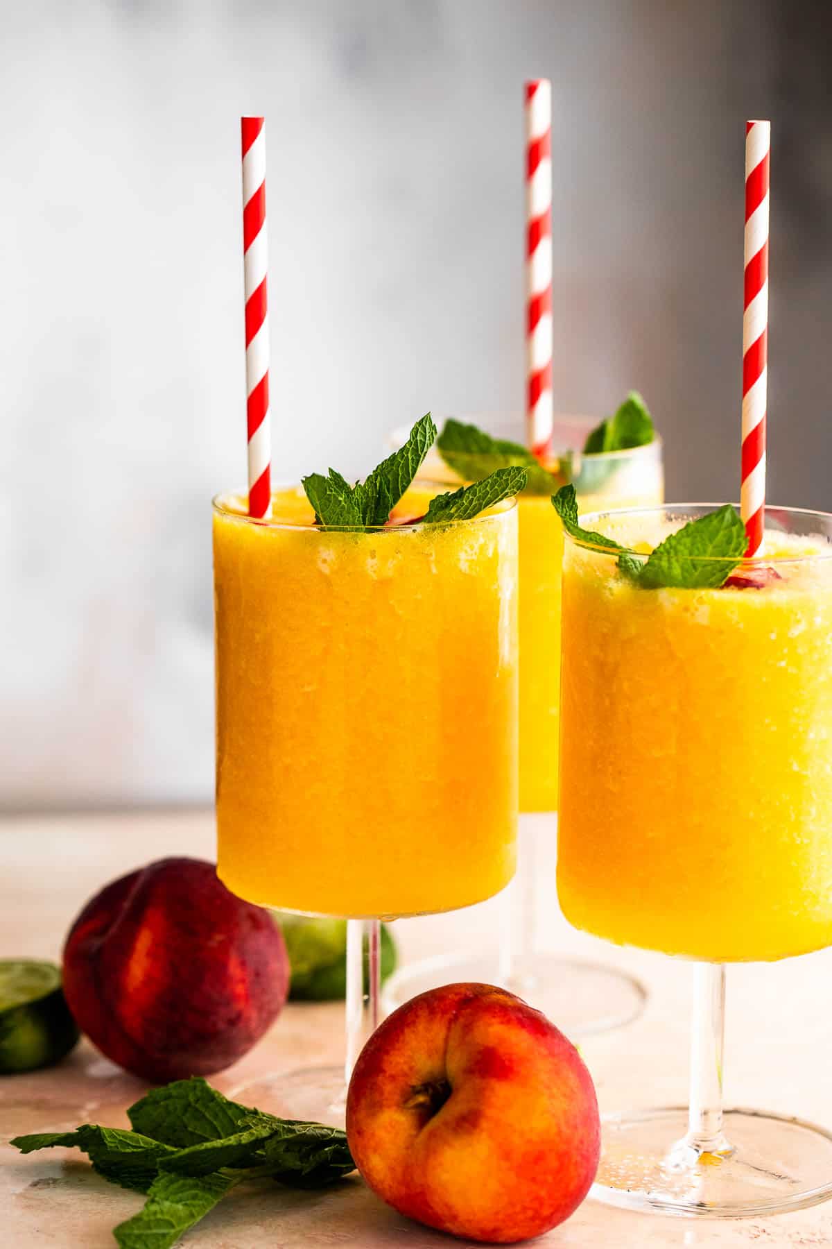 Peach Daiquiri Served in three glasses topped with straws and mint leaves