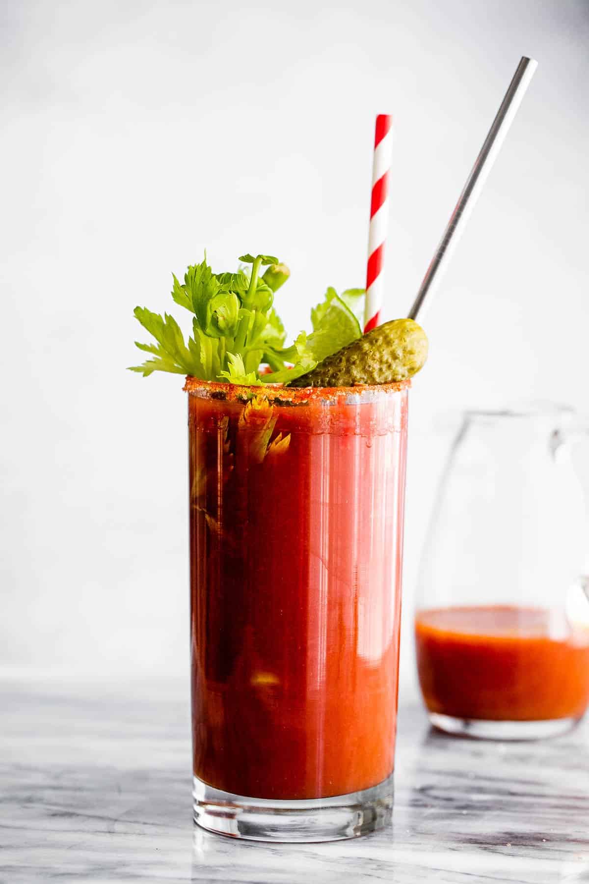 Bloody Mary cocktail garnished with straws, pickles and celery sticks