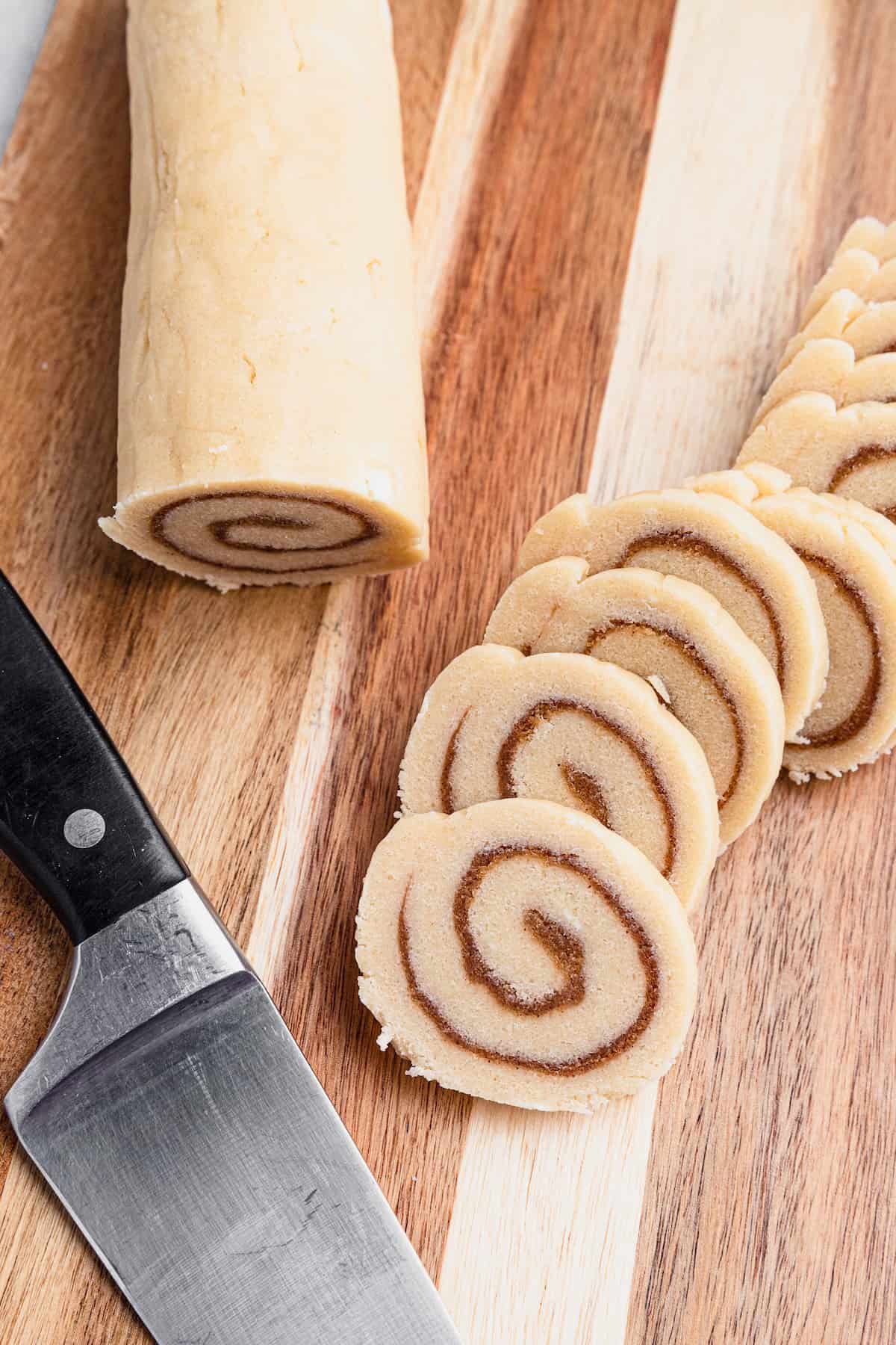 The Log of Rolled Cookie Dough Beside a Sharp Knife and Cut Out Cookies