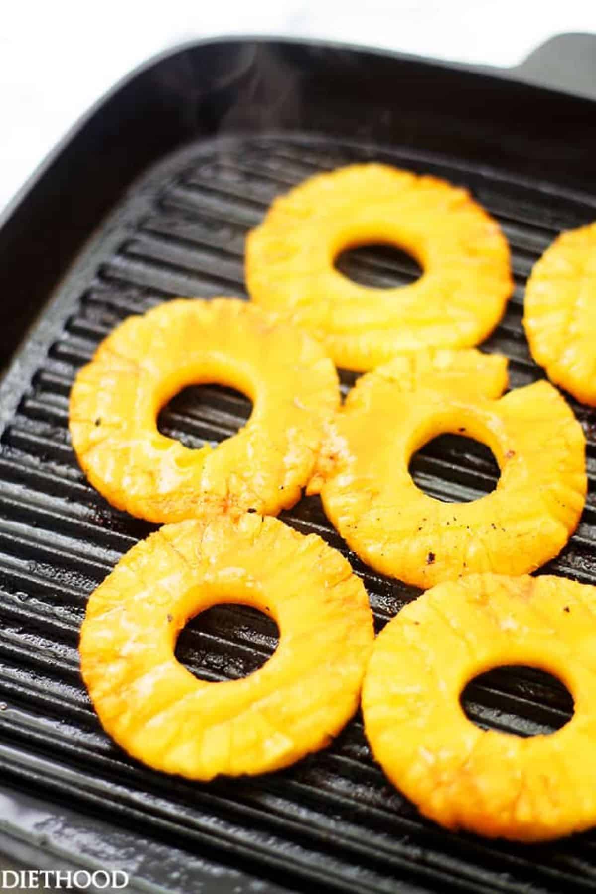 Sliced pineapple rings on a grill pan.